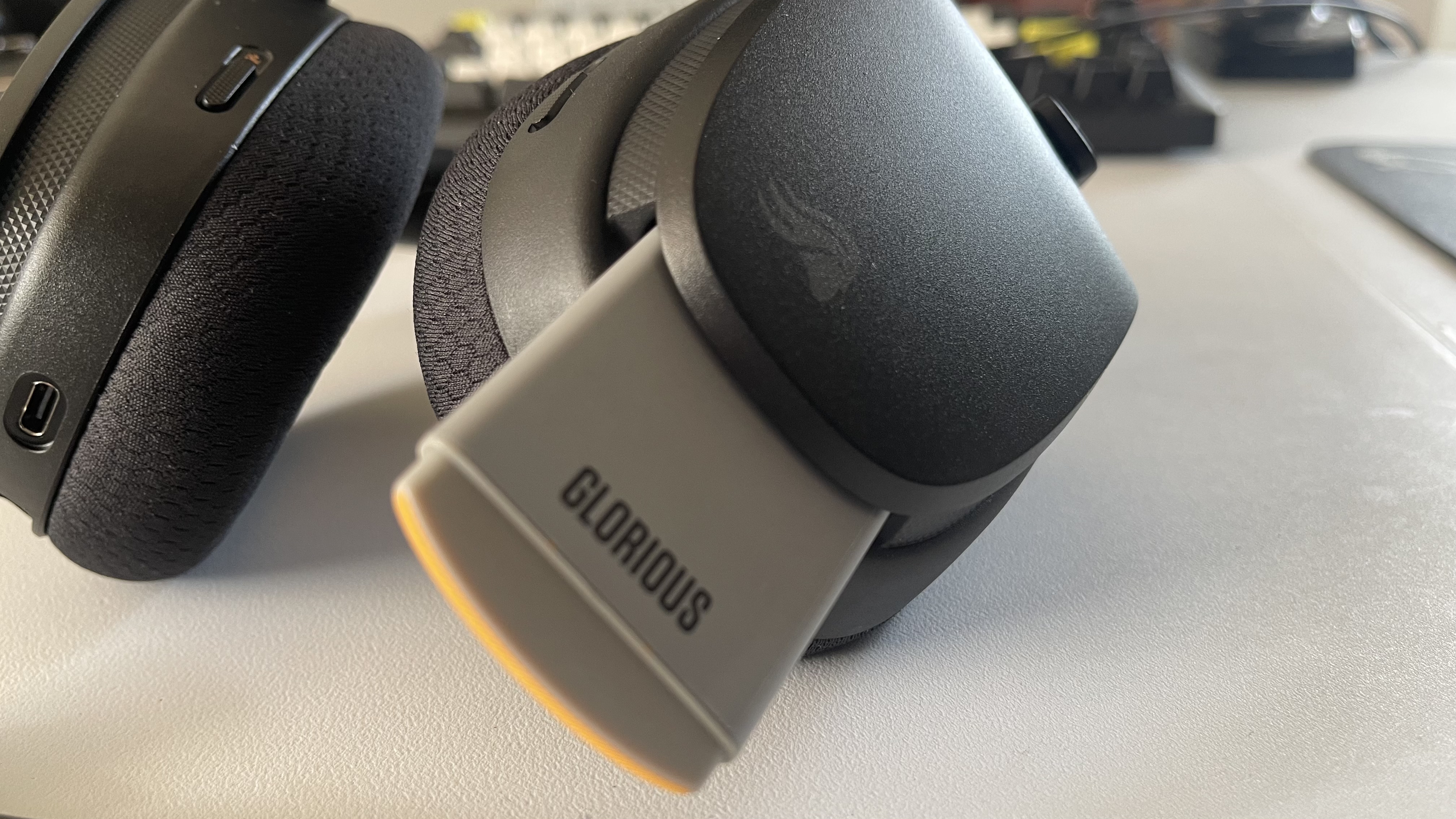 The Glorious GHS Wireless InfinitePlay gaming headset in black and orange on a plain white desktop.