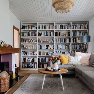 A living room with a wall of bookshelves, a couch and a coffee table