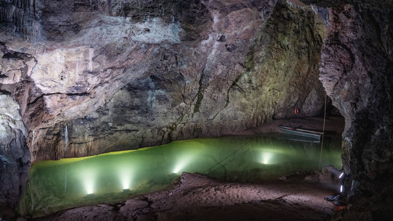 Cave system with large pool of water, lit by spotlights