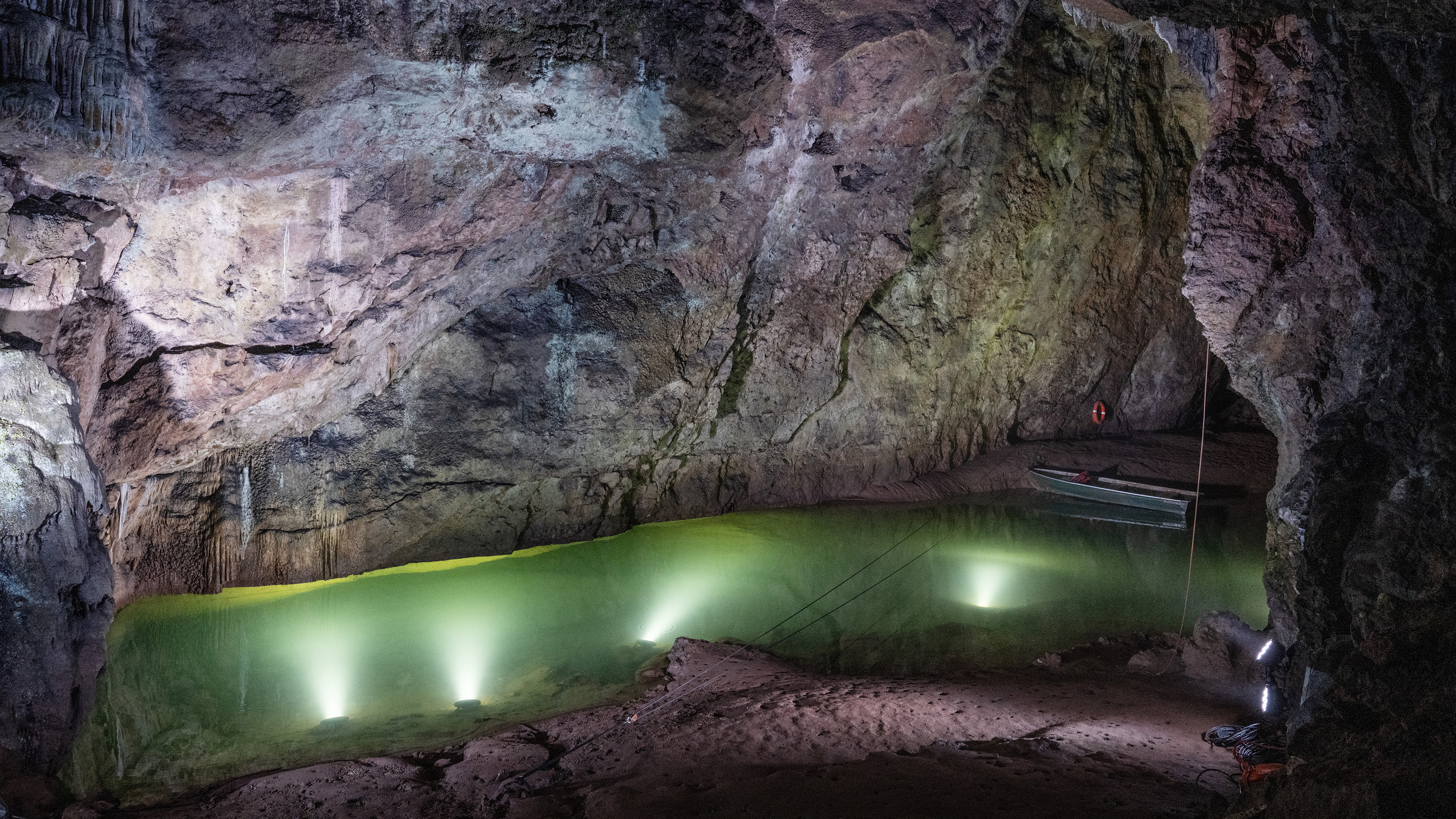 Cave system with large pool of water, lit by spotlights