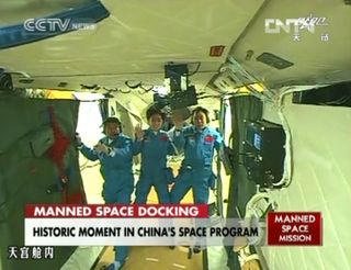 The crew of China's Shenzhou 9 mission waves to a camera aboard the Tiangong 1 space module after successfully docking their capsule at the test module on June 18, 2012, in this still from a state-run TV broadcast on CNTV The crew is (from left) Liu Wang, Liu Yang (China's first female astronaut), and mission commander Jing Haipeng.