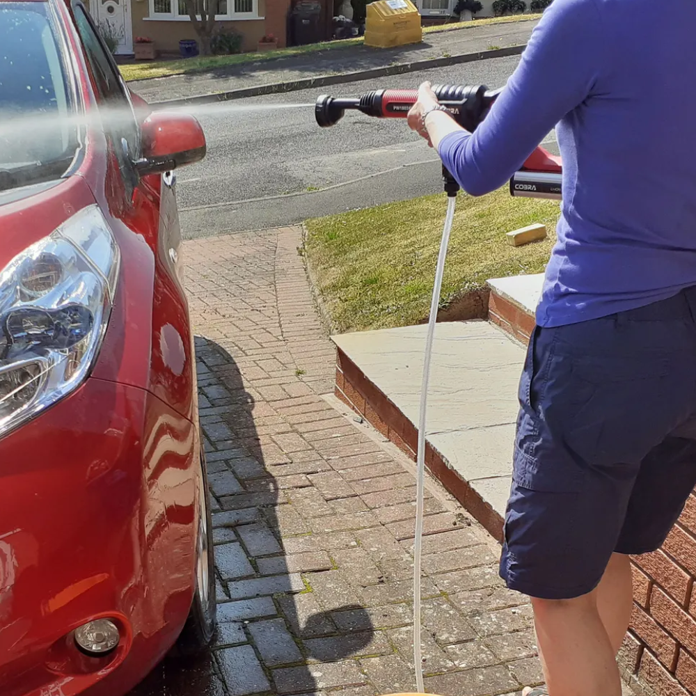 Person using the Cobra pressure washer on a red car