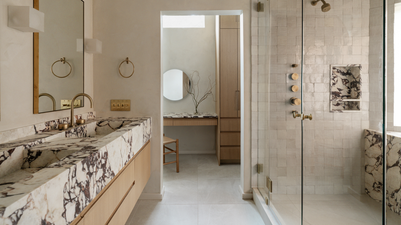 A calming bathroom design with a marble vanity, neutral tiles and an opening to a vanity area