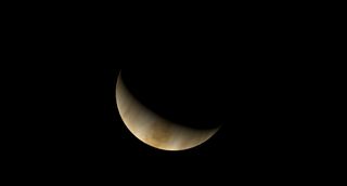 a small crescent of an orangish planet
