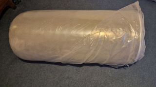 Winkbed Plus mattress still in it's rolled up state inside of a plastic material