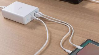 A picture of a USB charging station on a wooden surface, with multiple devices plugged into it