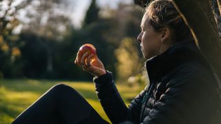 woman eating an apple while looking at nature