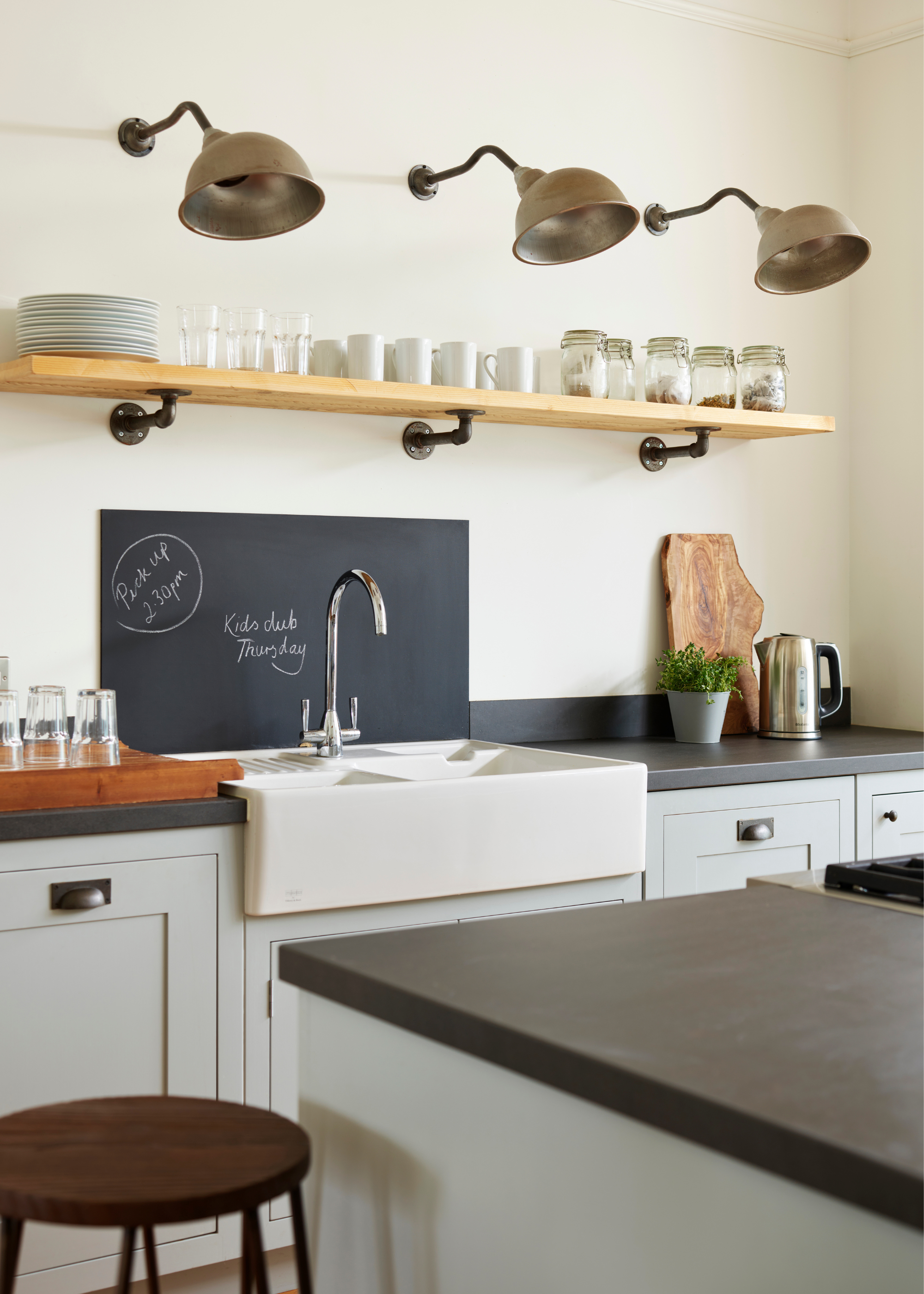a bistro kitchen with light blue cabinets, black counters, and rustic finishes