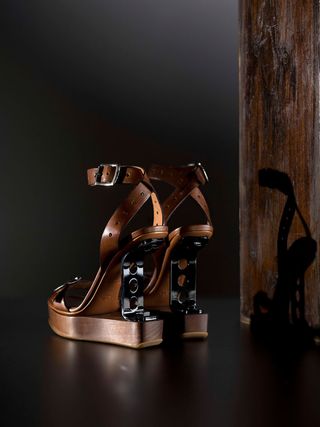 a pair of brown sandal high heels with a black metal bracket in the heel