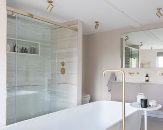 Neutral bathroom with brass hardware and glass privacy screen