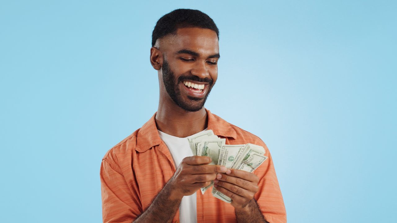 A young man smiles as he counts money.