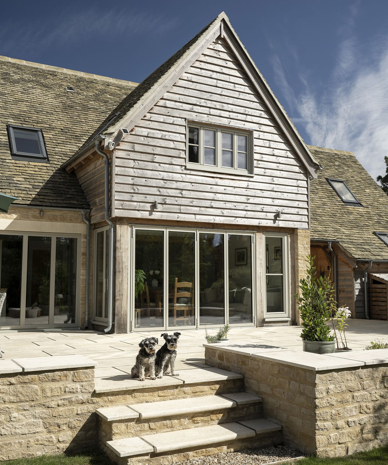 Two pups on a patio in front of a newly build oak frame home