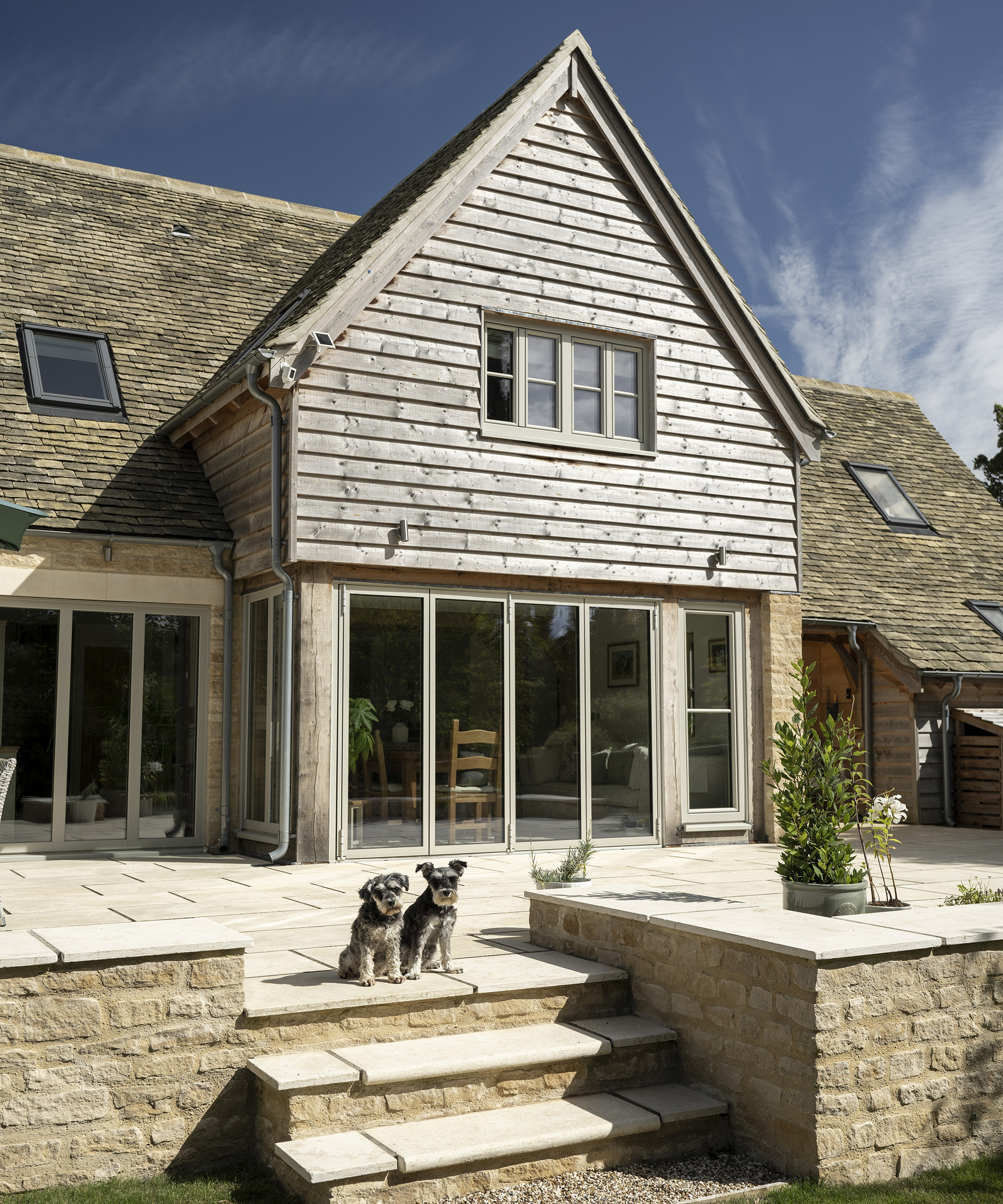 Two pups on a patio in front of a newly build oak frame home