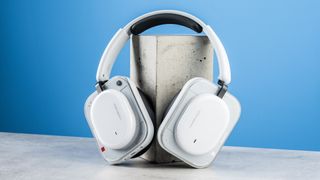 the nothing headphone (a) photographed against the blue tom's guide background, showing the transparent and white ear cups with red accents, the padded headband, and the accessories including 3.5mm jack