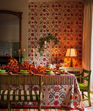 A red a neutral dining toom with a matching patterned tablecloth and wallpaper