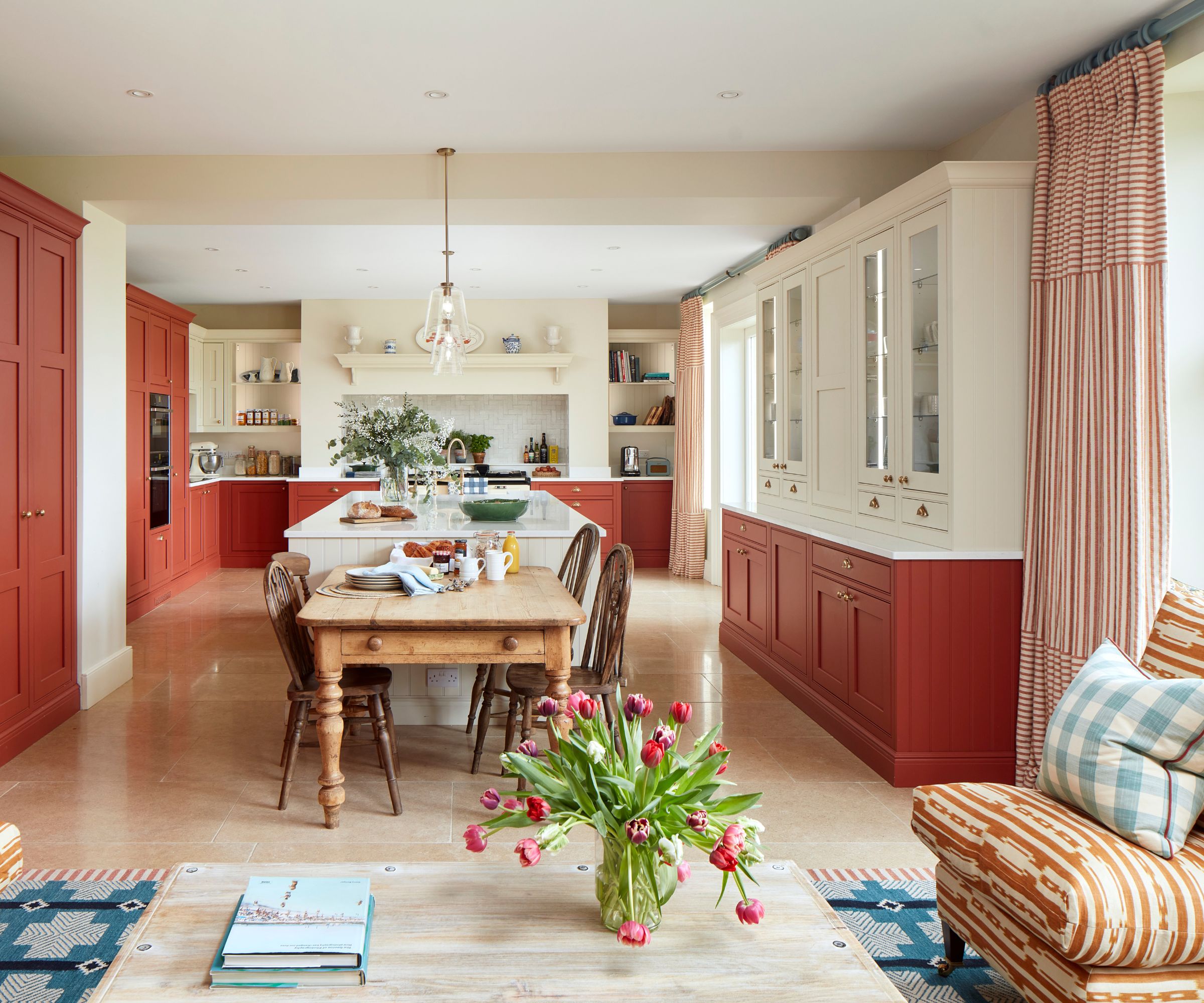 A red and white open plan kitchen with a blue rug to define the living area