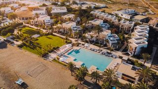 An aerial view of the Hotel Paracas in Peru shows the hotel's massive pool and buildings on a sunny day