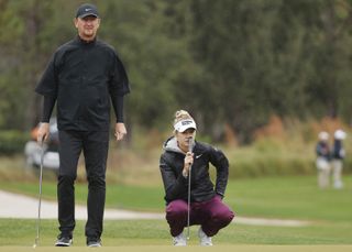 Nelly Korda lines up a putt whilst Petr Korda walks alongside her