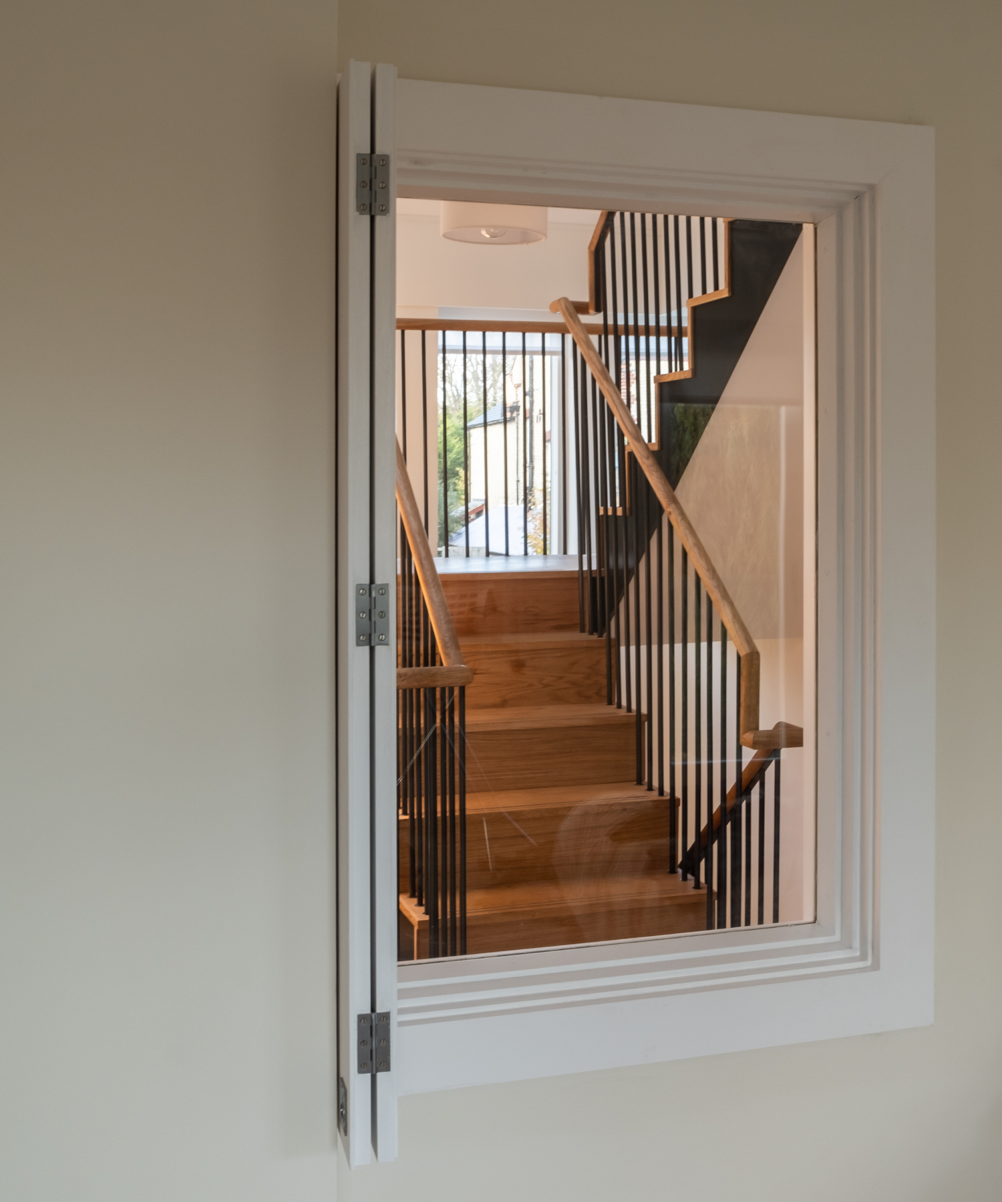 single fixed window in white frame on wall showing stairwell