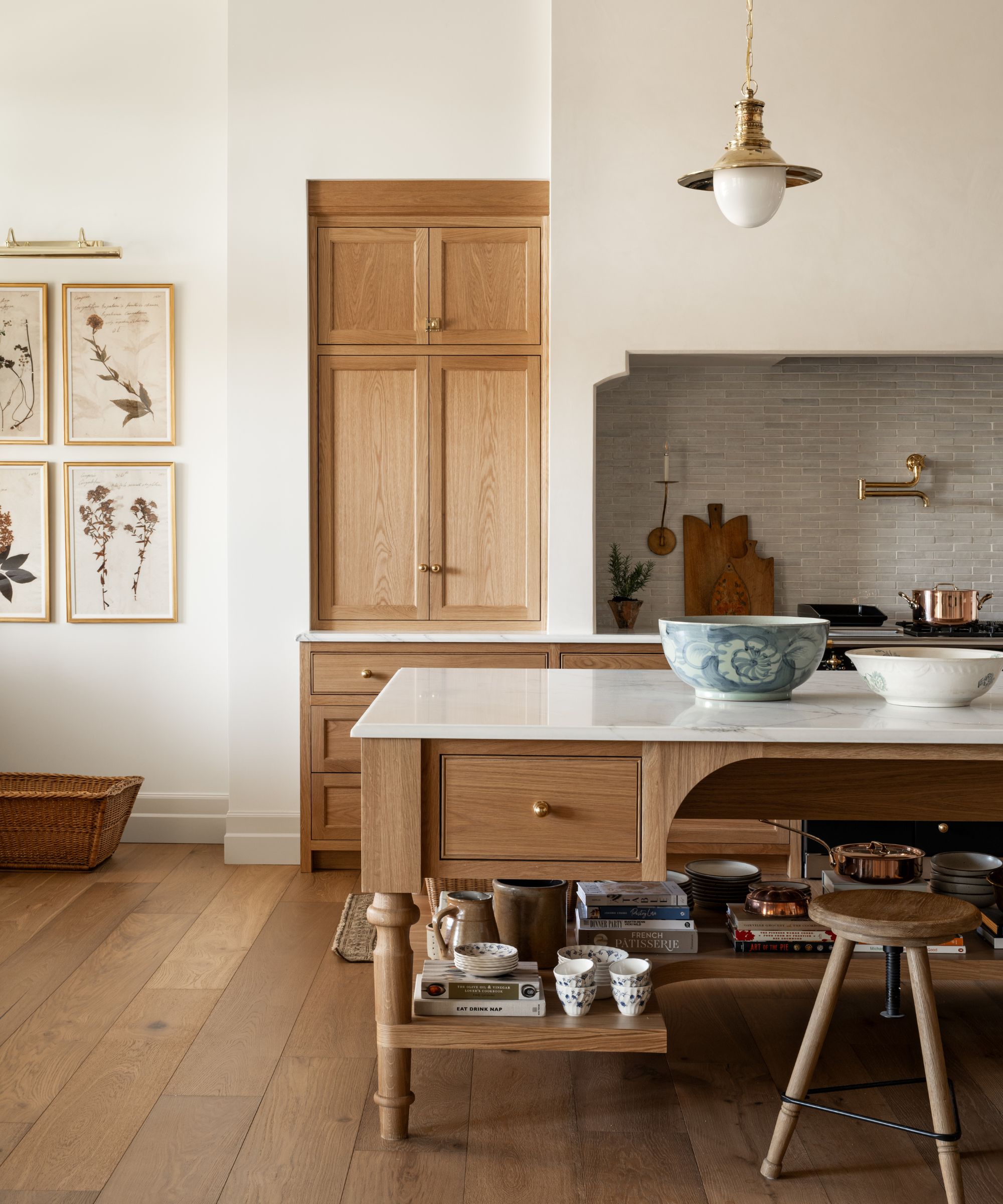 a layered oak kitchen by Studio McGee with a large marble topped island, a shapely cooker hood and vintage decor