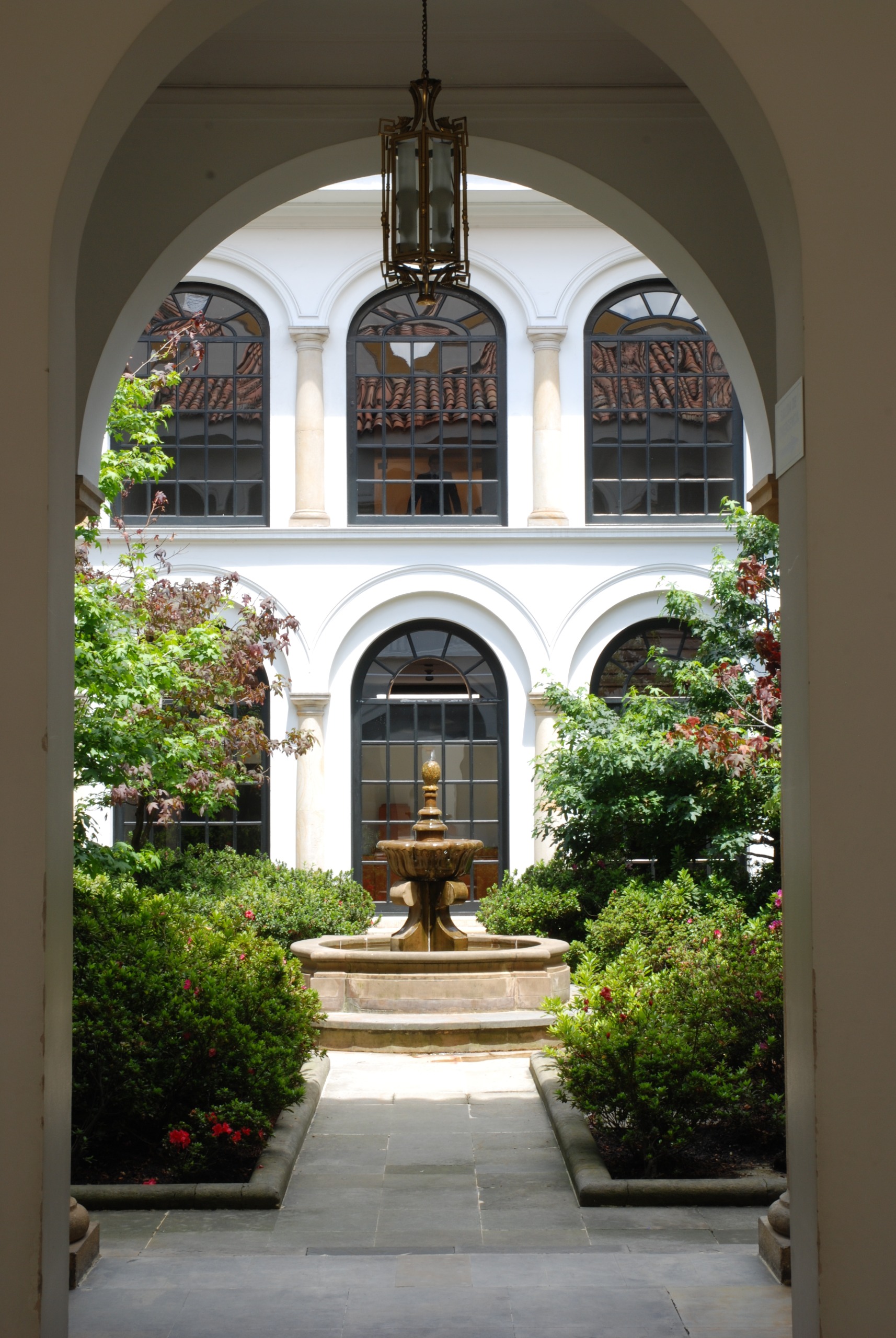 An ornate inner courtyard with leafy plants and a central fountain.
