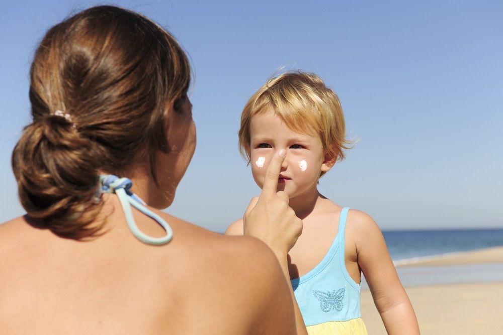 Mother applying sunscream to her daughter