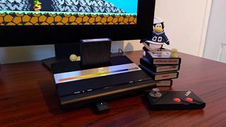 Atari 7800+ sitting on desk connected to monitor next to cartridges and controller with Bentley Bear's Crystal Quest on screen