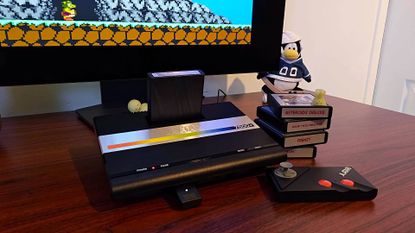 Atari 7800+ sitting on desk connected to monitor next to cartridges and controller with Bentley Bear's Crystal Quest on screen
