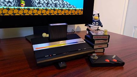 Atari 7800+ sitting on desk connected to monitor next to cartridges and controller with Bentley Bear's Crystal Quest on screen