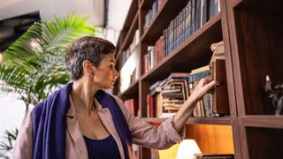 A woman peruses books on a bookshelf