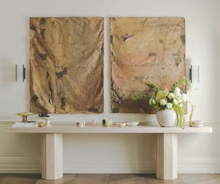 wide marble modern console table with art in background and vase og flowers on it