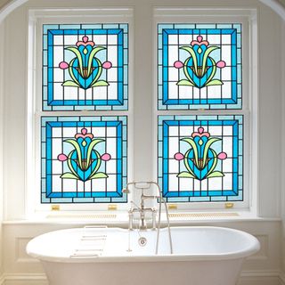 bathroom with freestanding bath and large windows covered with stained glass effect from purlfrost