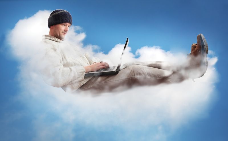 A man sits aloft on a cloud, working on his laptop