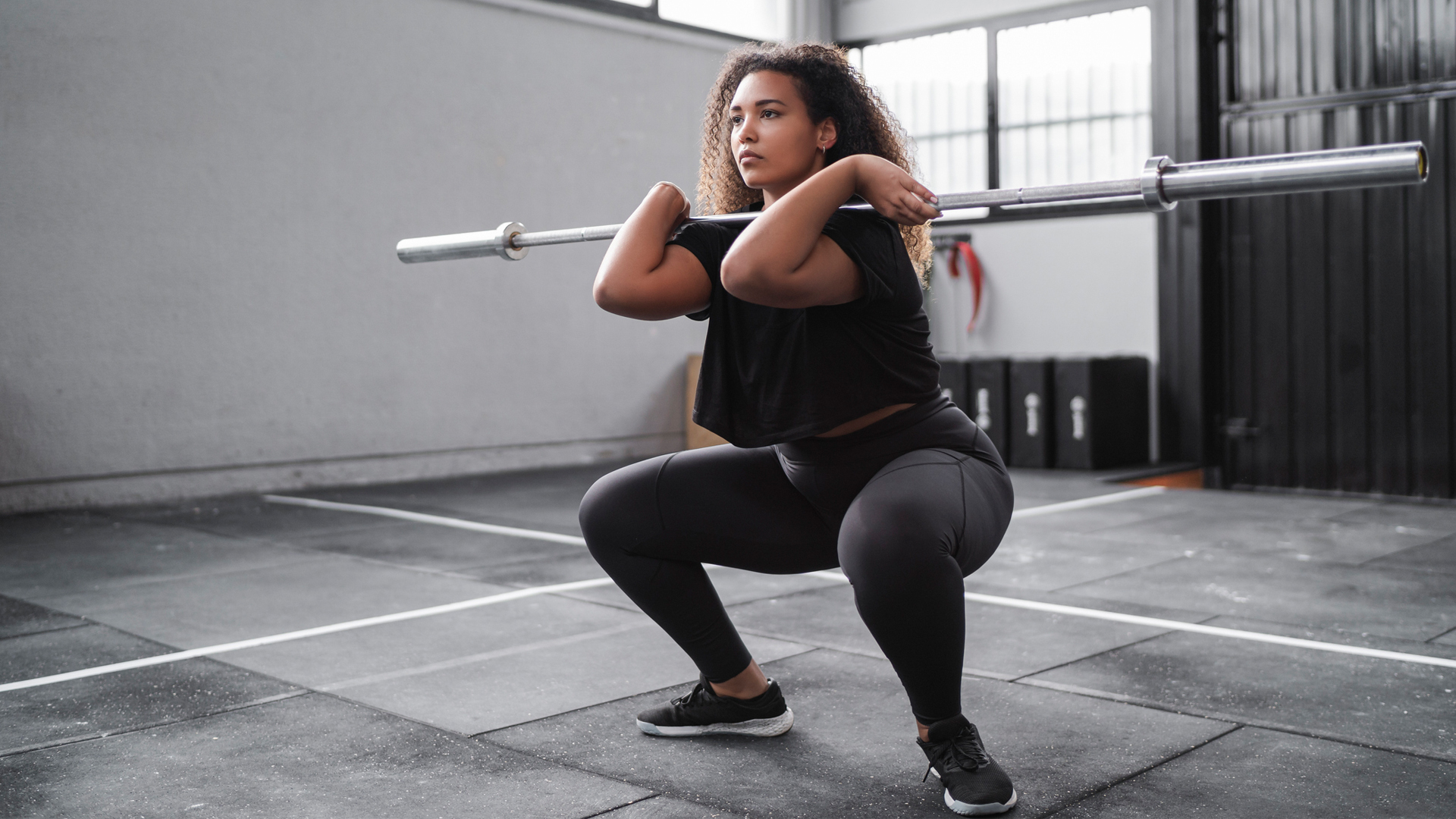 woman using a barbell to perform a front loaded squat