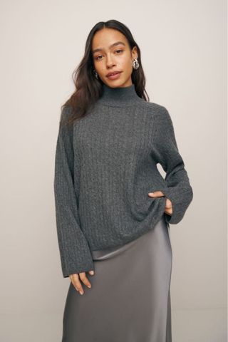 reformation winter sale woman wearing grey cableknit cashmere jumper with silk skirt