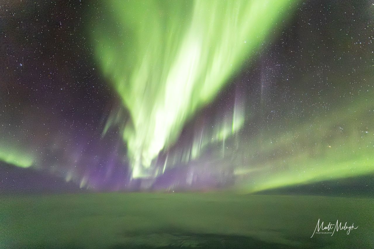 ribbons of green and purple light fill the sky in photos captured above the clouds from a dreamliner airplane.