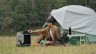 Man using EcoFlow Wave in front of tent while camping in the woods