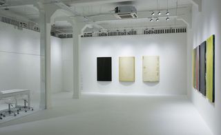 A white gallery displaying several pieces of artwork on the walls