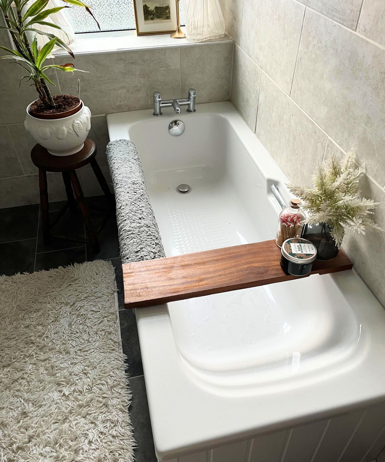 A tidy white bathtub in a tiled bathroom.