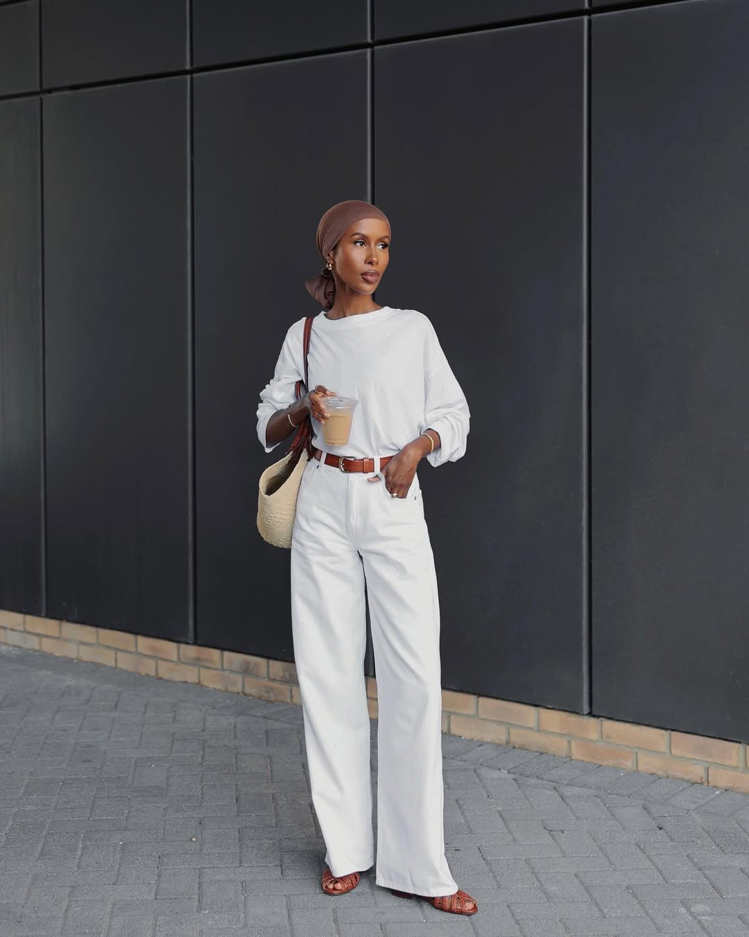 @basma_k wears a white blouse, white jeans and tan fisherman sandals