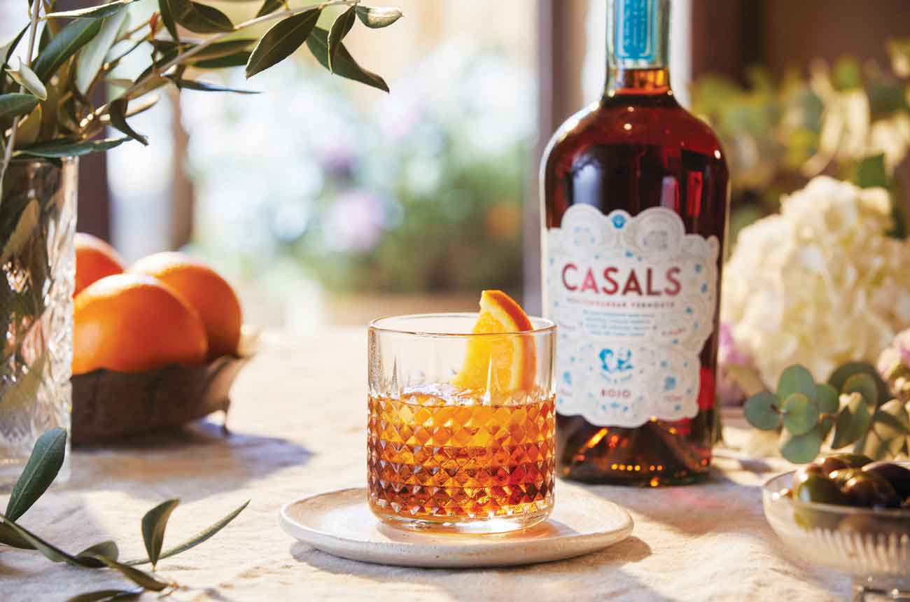 Bottle of Casals Mediterranean Vermouth and glass of the same on a table