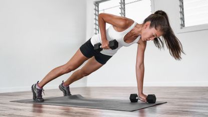 A woman performing a renegade row with dumbbells