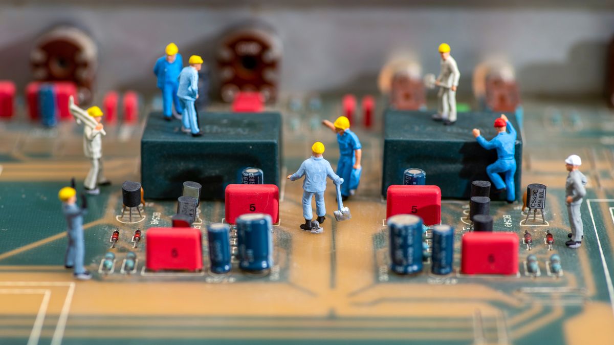 A close up photo of a computer motherboard with miniature figures of workmen placed on top, to represent the right to repair.