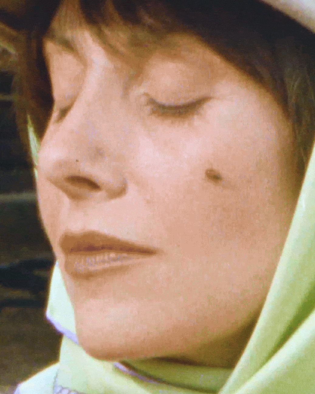 a gif of alison brie laughing wearing a headscarf