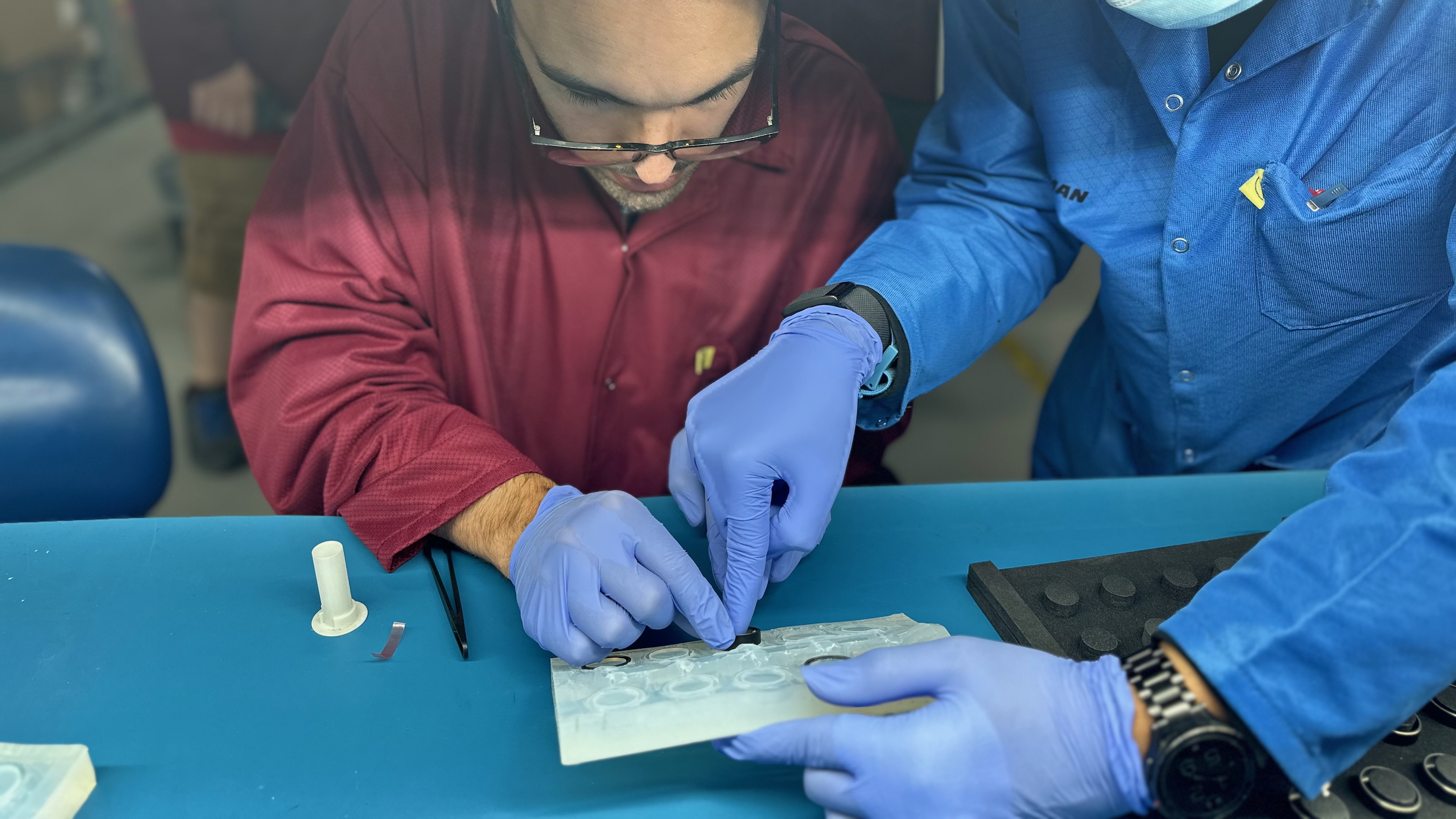 The author placing the self-made Ultrahuman Ring Air into a silicone mold with the help of a factory worker.