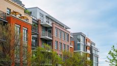 Apartment building and green trees under a blue sky.