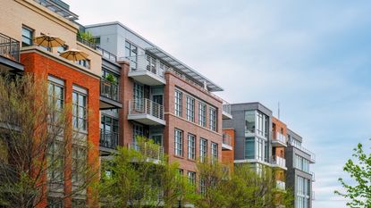 Apartment building and green trees under a blue sky.