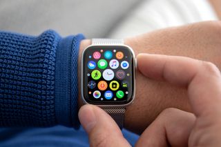 Image of an Apple Watch on a man's wrist with many different app icons on the watch screen