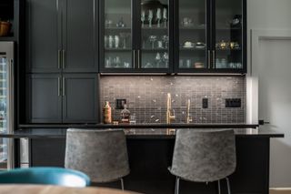 Black kitchen cabinets, black countertop and black tiled splashback