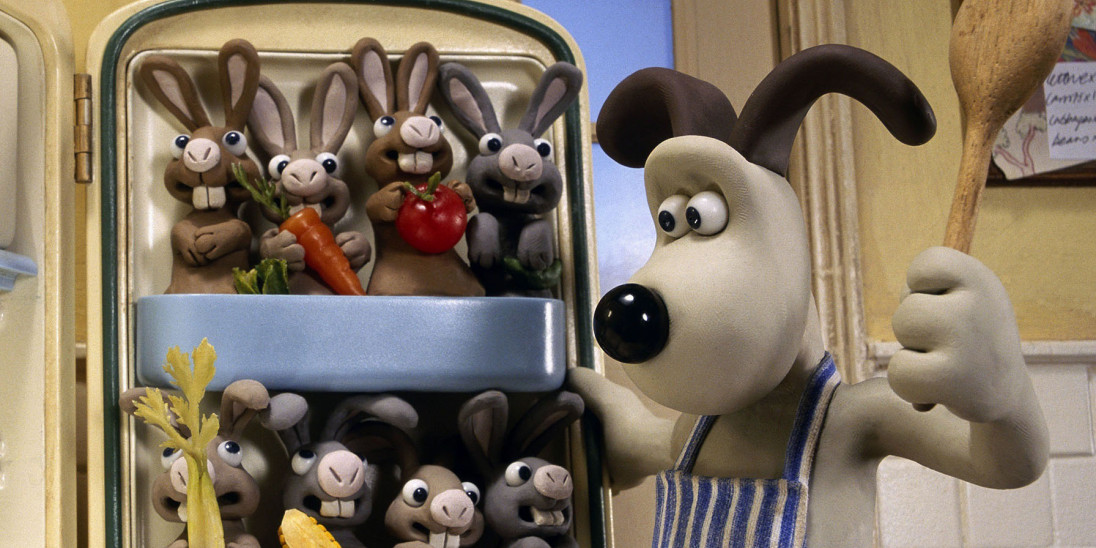 Gromit holding a spoon, looking at a group of rabbits sitting in his fridge